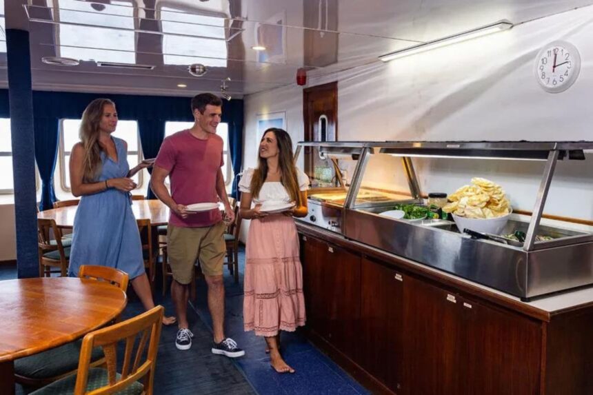 Crew members serving guests from a buffet spread in the OceanQuest dining area