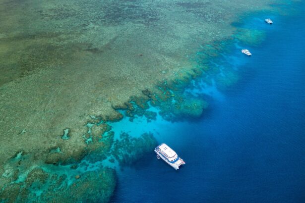 Aerial view of the OceanQuest catamaran near a coral reef edge with two smaller boats nearby