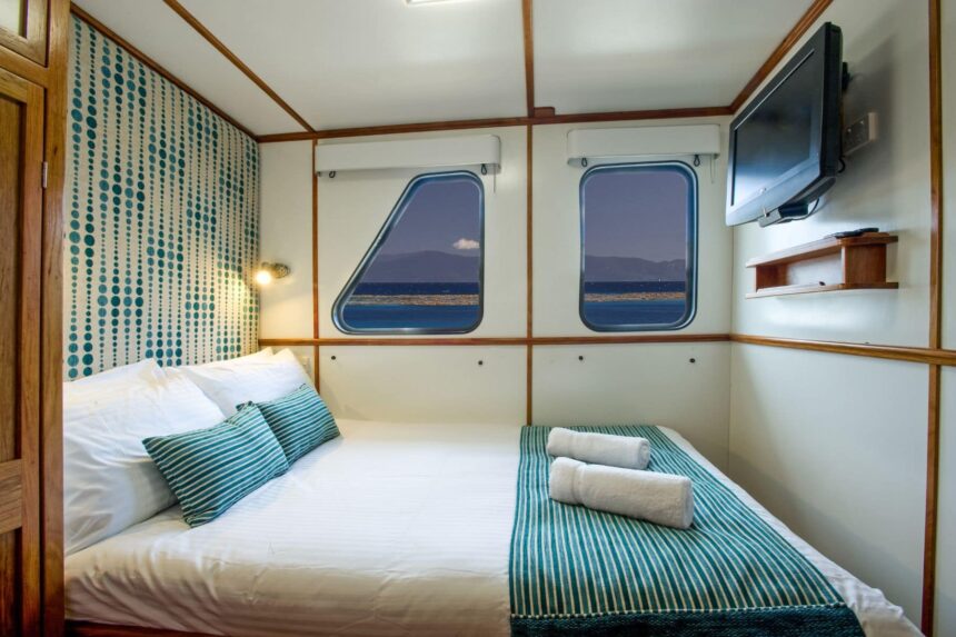 Twin cabin aboard Spirit of Freedom with teal patterned bedding and a TV