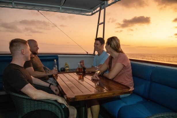 Four guests sharing drinks on deck as the sun sets over the water