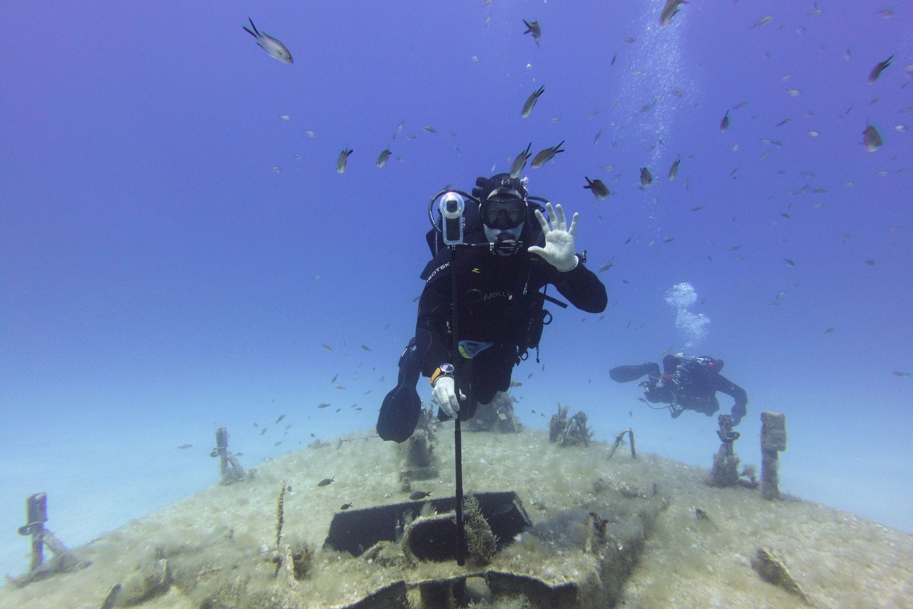 DIVEIN tester waving while filming with an Insta360 X4 on a pole above a wreck