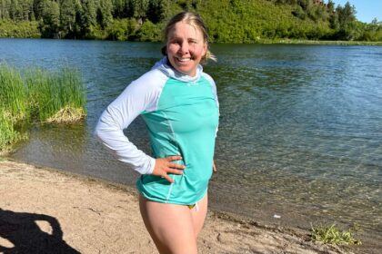 DIVEIN tester wearing the teal and white BARE Eclips hooded rash guard on a lake shore