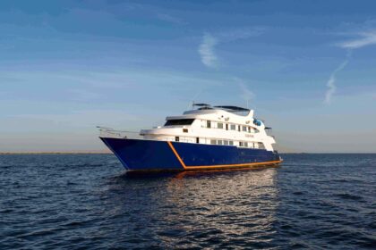 White and navy liveaboard dive boat at anchor on calm open water