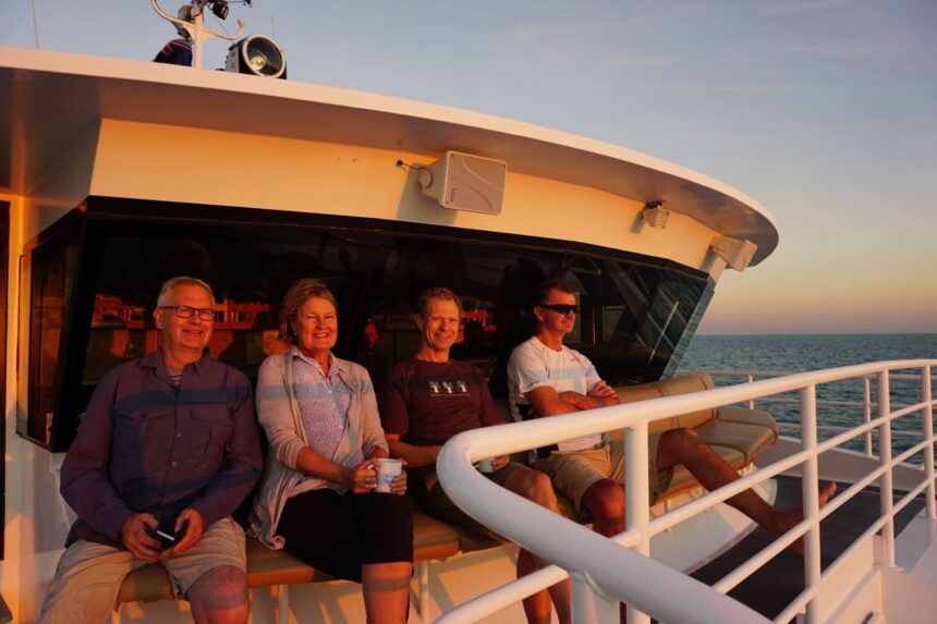 Group of guests sitting together on deck at sunset