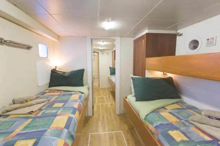 Twin bunk cabin with patchwork bedding and wood-paneled hallway