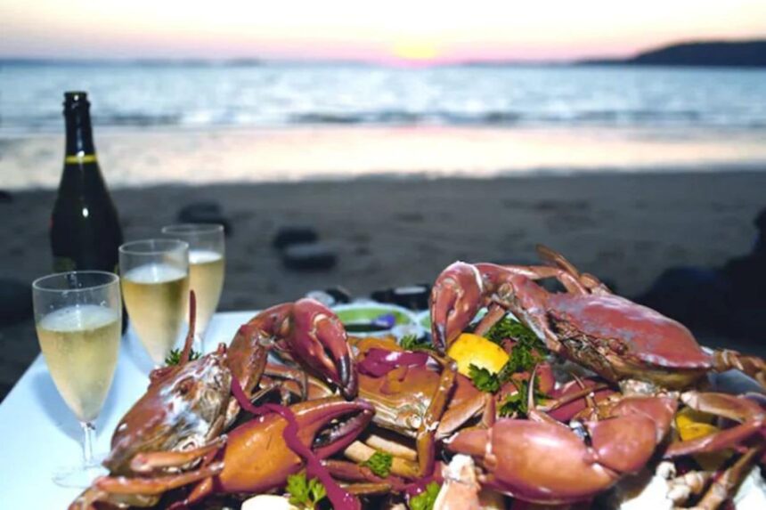 Platter of cooked crab served beachside with champagne at sunset