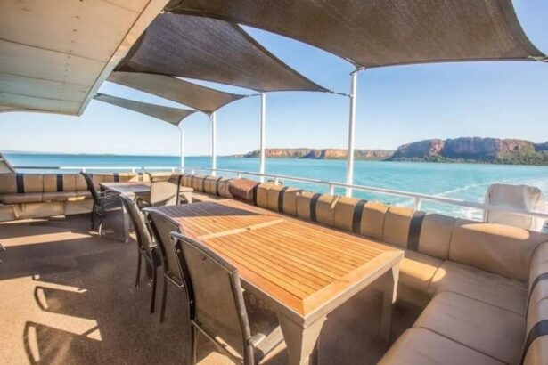 Wooden dining table set under shade sails with ocean view