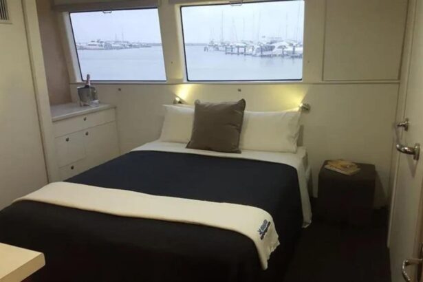 Cabin bed with navy linens and a window overlooking the harbor