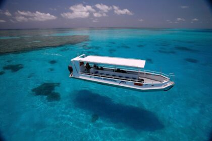 Odyssey Explorations dive tender floating above vivid turquoise reef water, aerial view