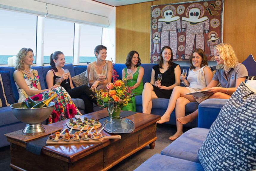 Group of women socializing with champagne in the liveaboard lounge