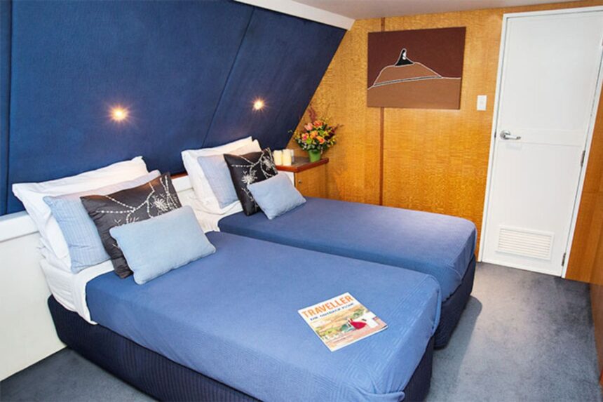 Twin cabin with navy bedspreads and wood-paneled walls