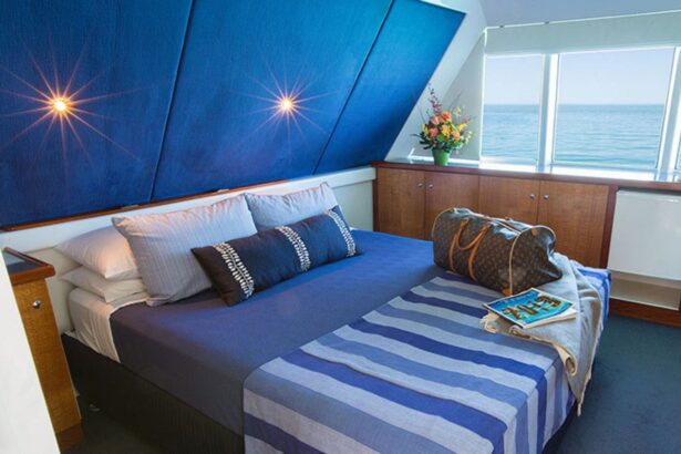 Blue accented cabin bedroom with queen bed and ocean view aboard MV Great Escape