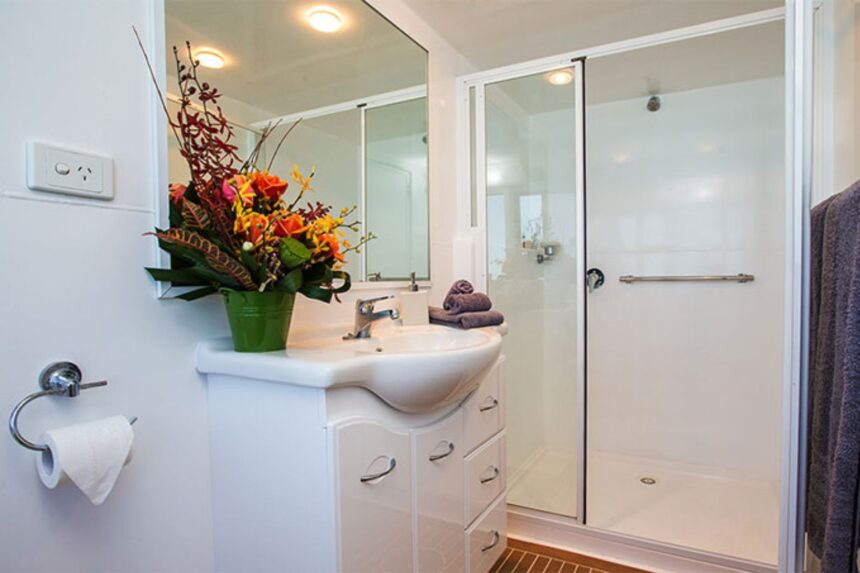 Bathroom with vanity sink, flowers and glass shower stall