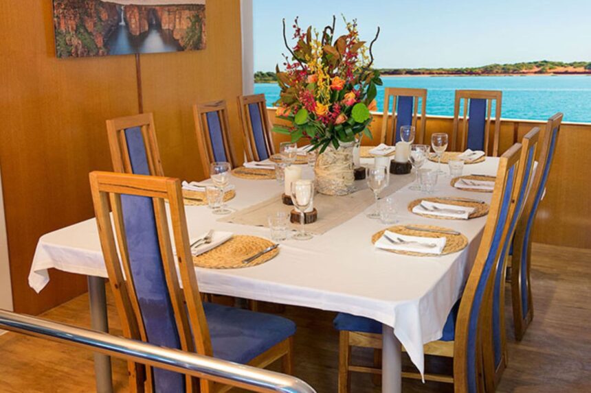 Indoor dining table set for guests with ocean views aboard MV Great Escape