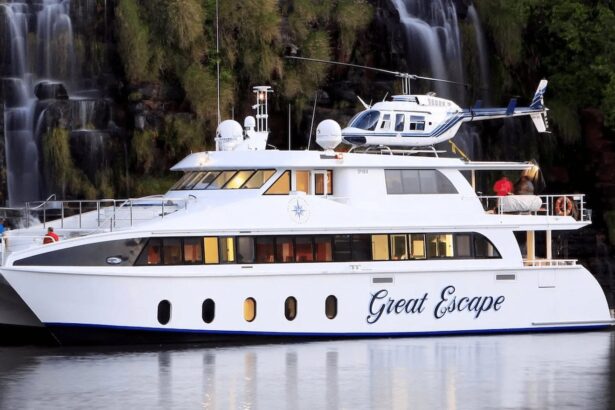 MV Great Escape anchored near a waterfall with its onboard helicopter on deck