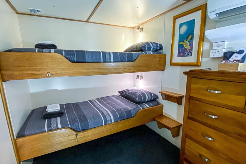 Bunk cabin aboard the Spoilsport with made-up beds and a framed print on the wall