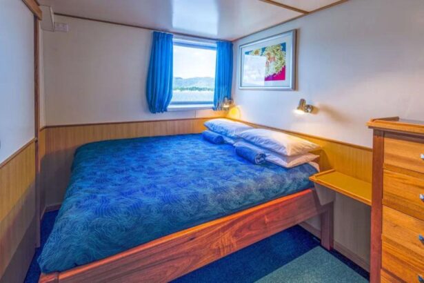Cabin aboard the Spoilsport with a queen bed, wooden dresser and curtained window