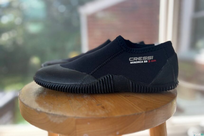 Cressi Minorca SB 3 mm low-cut dive boot in side profile on a wooden stool by a window