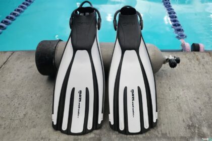White and black Mares Avanti Quattro Plus fins leaning against a scuba tank at the poolside