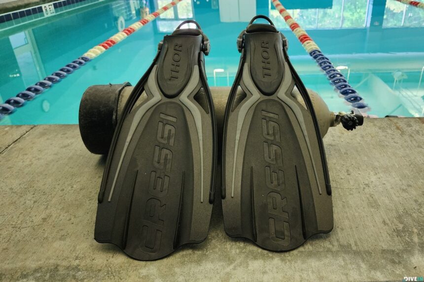 Pair of black Cressi Thor EBS paddle fins standing against a tank at the poolside