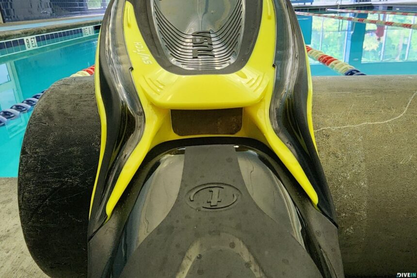TUSA Hyflex Switch In Flash Yellow TUSA Hyflex Switch fin in flash yellow propped against a scuba tank at the edge of a pool