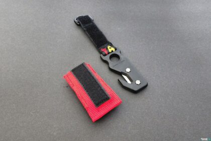 Dive Rite line cutter in black with its hook-and-loop wrist strap and red pouch laid alongside