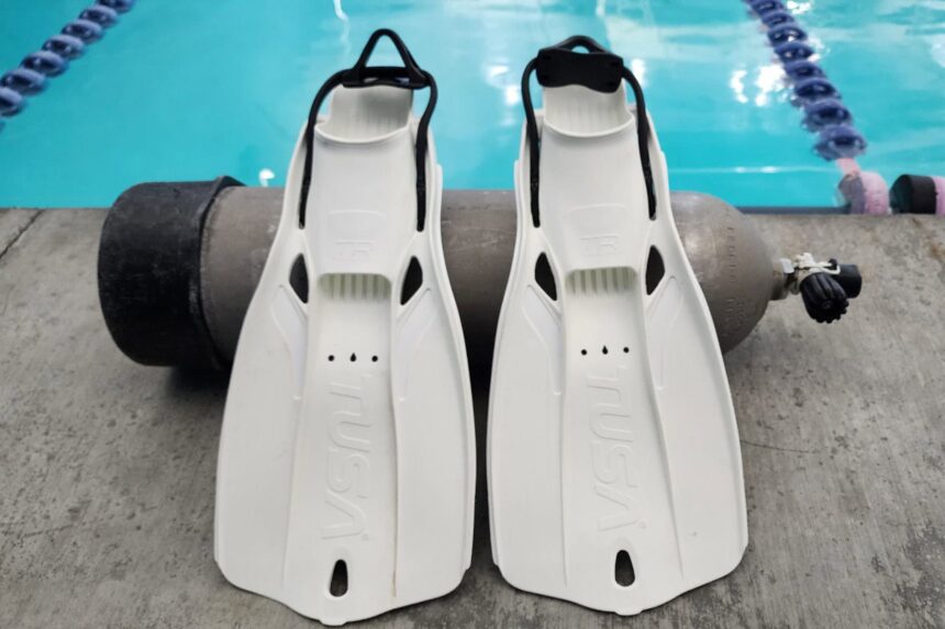 Travel Right Fins At The Pool Pair of white TUSA Travel Right fins standing against a scuba tank at the poolside