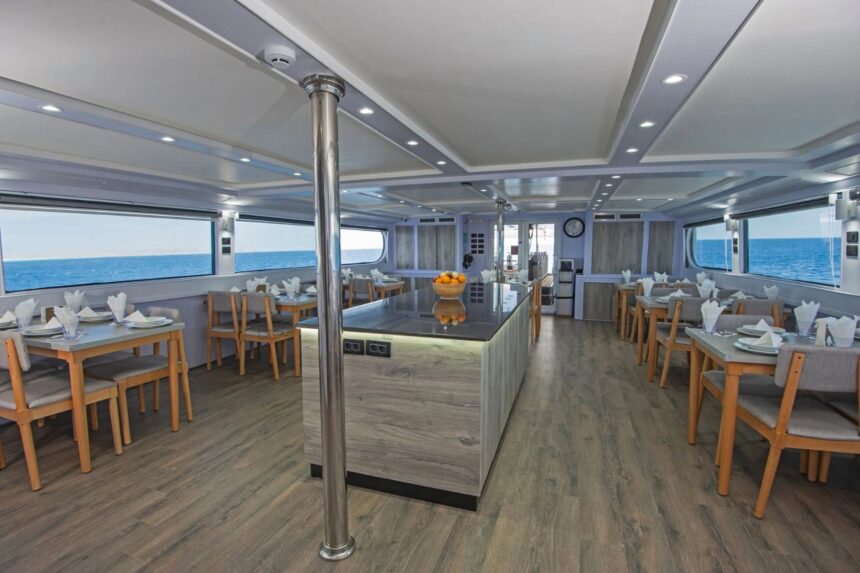 Dining room aboard the Blue Horizon liveaboard with wooden tables and a central island counter