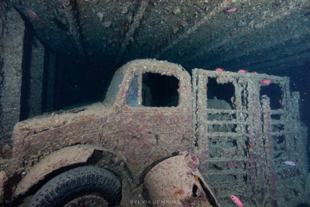Coral-encrusted truck wreckage resting on the seabed inside a sunken ship