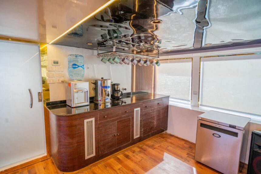 A galley counter aboard the Hammerhead II with hanging mugs, a water cooler and coffee maker