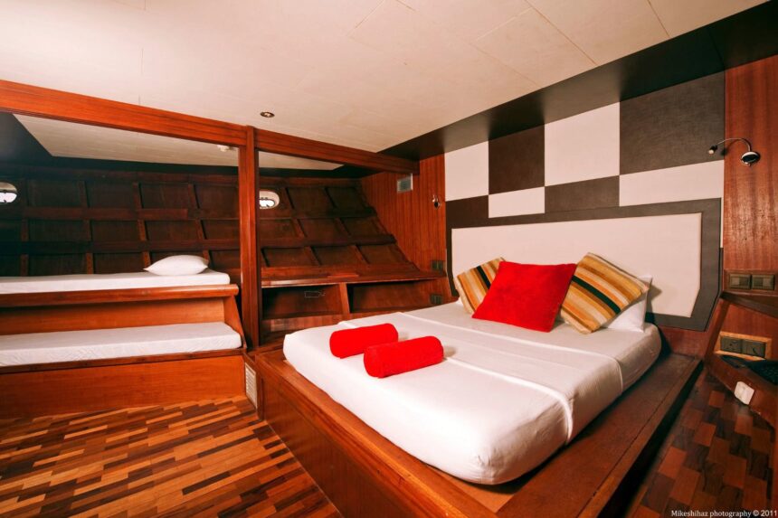 Twin bunk cabin aboard MV Theia with red accent pillows on the beds