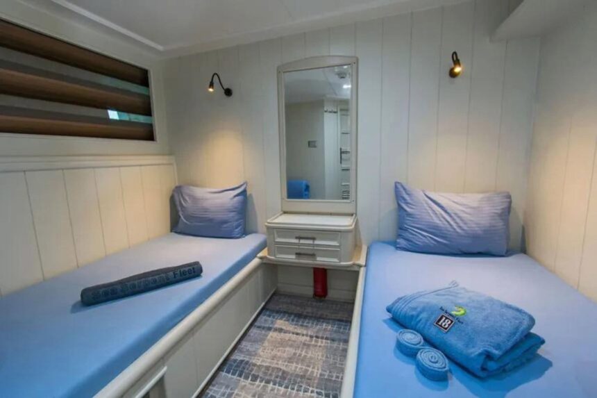 Twin cabin with two single beds and a vanity mirror aboard the Sea Serpent Contessa