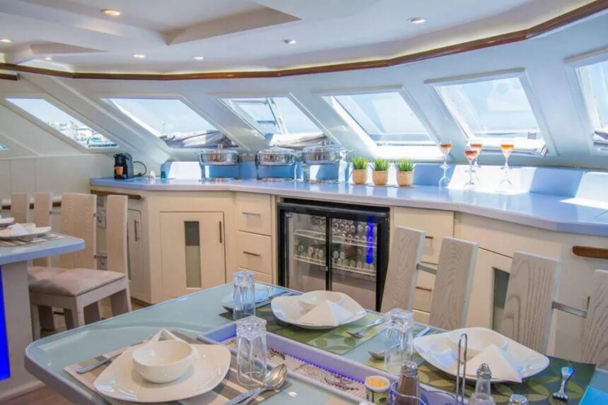 Dining table set with wine glasses beneath skylight windows on the Sea Serpent Contessa