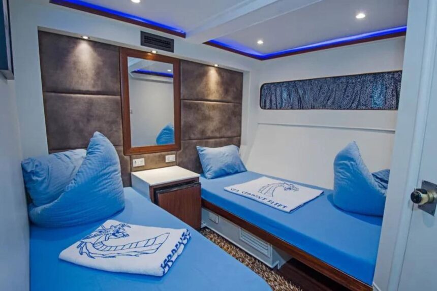 twin cabin with blue bedding and mirror vanity aboard the Sea Serpent