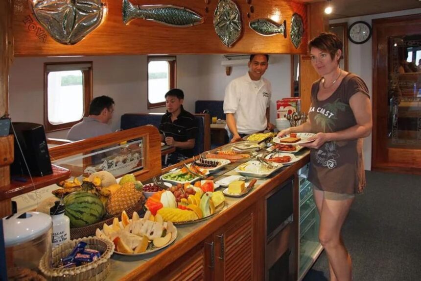 Guest at the buffet counter loading a plate as crew prepare fresh fruit and pastries aboard the Ocean Hunter III