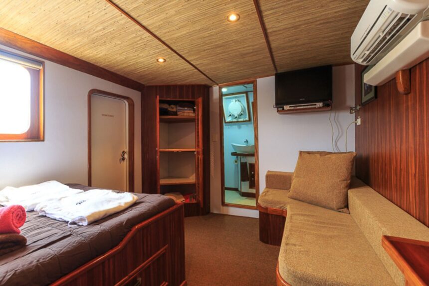 Liveaboard cabin with a wooden bed, built-in sofa and ensuite bathroom on the Ocean Hunter III