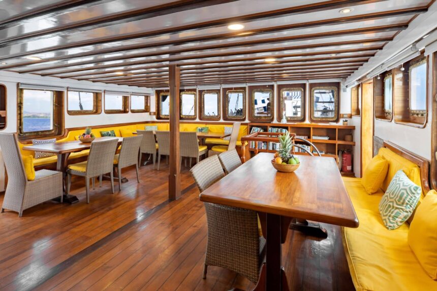Dining salon on the MSY Seahorse with wooden tables and yellow cushioned booth seating