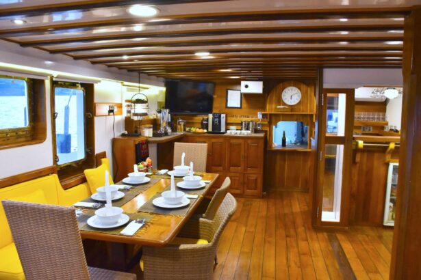 Dining salon on the MSY Seahorse with a table set for a meal, a TV and a wall clock