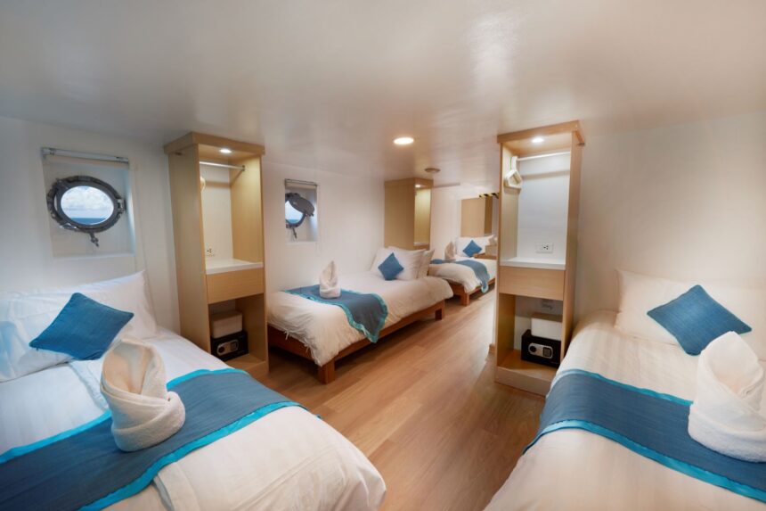 Twin-bed cabin aboard the Solitude One with portholes and built-in wardrobes