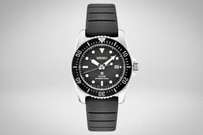 Seiko SNE573 Prospex Solar dive watch with black dial and black rubber strap on a grey background