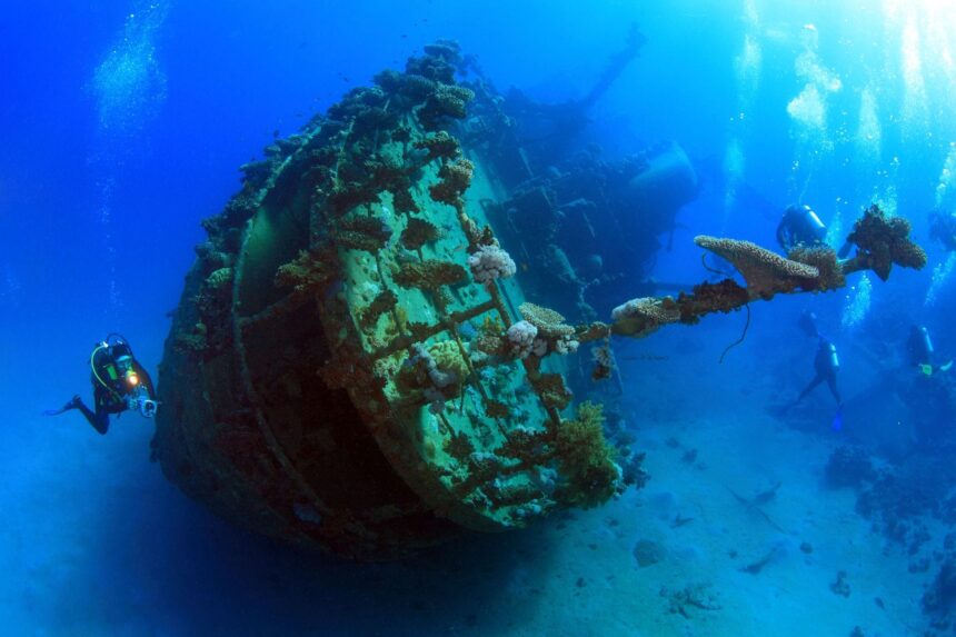 Diver exploring a coral-encrusted shipwreck underwater