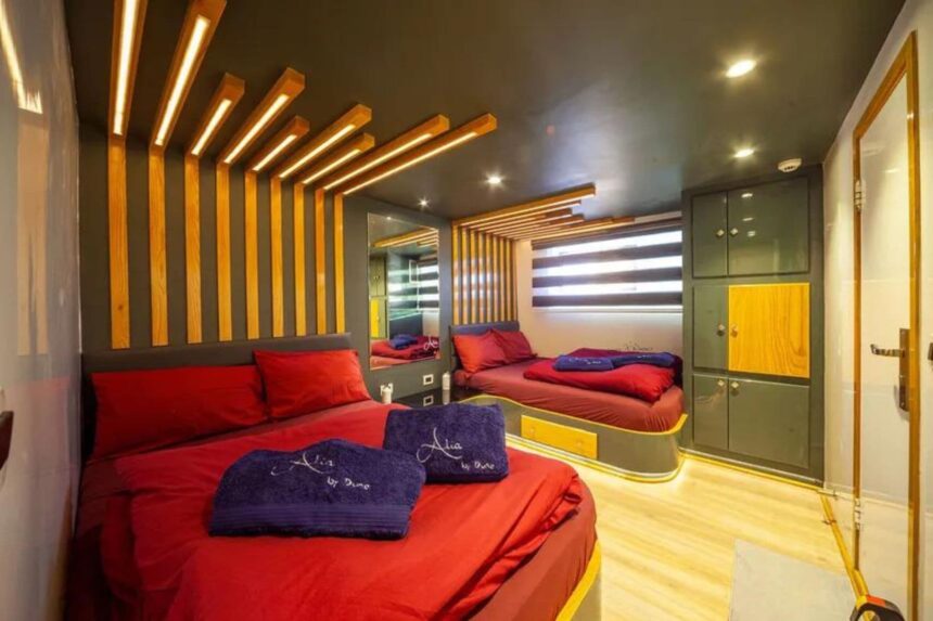Cabin aboard the Alia liveaboard with red bedding and wood-slat headboard