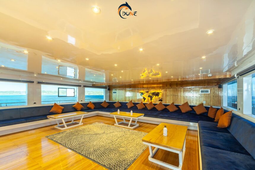 Indoor lounge with blue sofas and a world map wall aboard the Alia