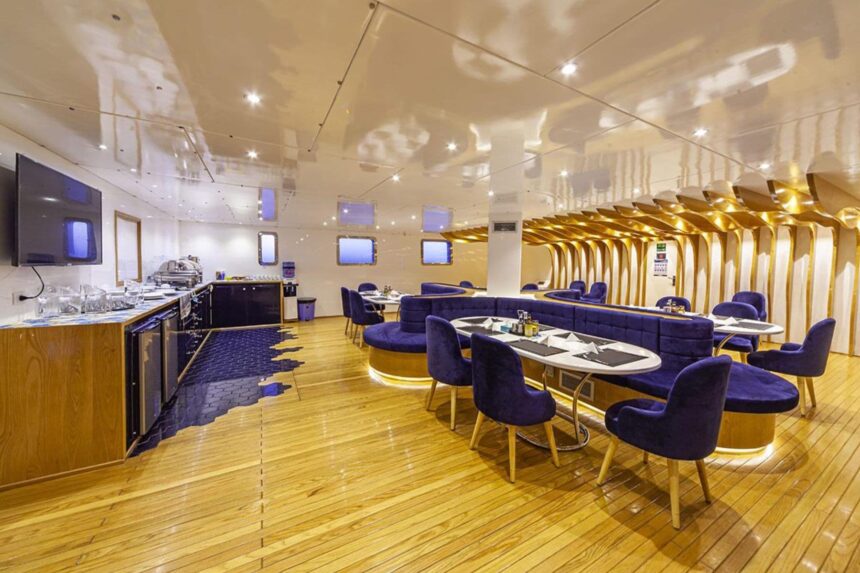 Dining tables and blue velvet chairs aboard the Alia liveaboard