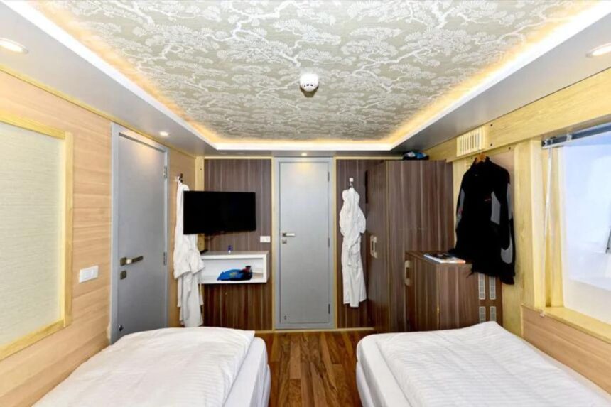 Twin bed cabin aboard the MY Blue with wardrobe and a wetsuit hanging