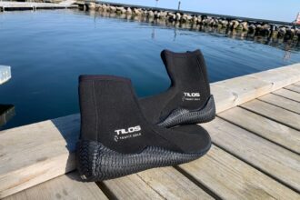 Tilos TruFit dive boots on a wooden dock beside calm harbour water during DIVEIN testing