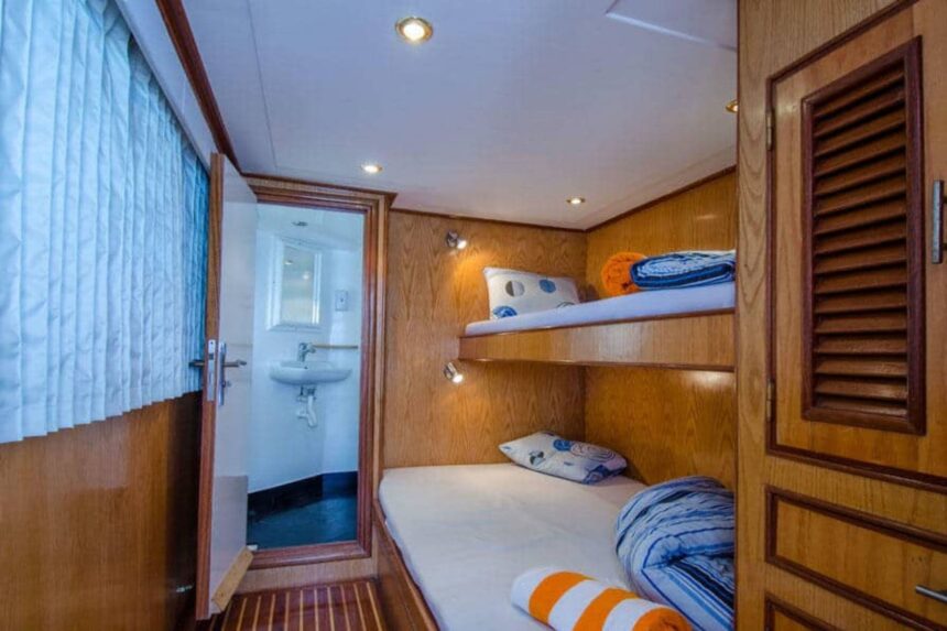 Wood paneled twin cabin aboard the MY Blue Planet 1 with louvered wardrobe doors