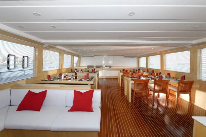Indoor dining salon with red cushions and wooden tables on the MY Blue Pearl