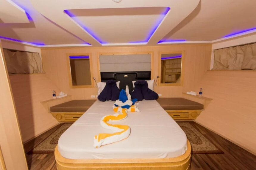 Cabin bed decorated with folded towel animals under mood lighting on the MY Blue Seas