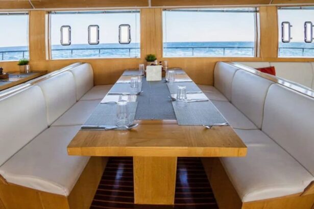 Long dining table set for guests beside windows overlooking the sea on the MY Blue Seas